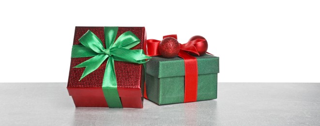 Photo of Christmas gifts in beautiful decorated boxes on grey table against white background