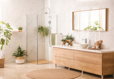 Photo of Stylish bathroom interior with countertop, shower stall and houseplants. Design idea