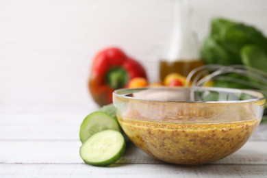Photo of Tasty vinegar based sauce (Vinaigrette) in bowl and cucumber on wooden rustic table, closeup. Space for text
