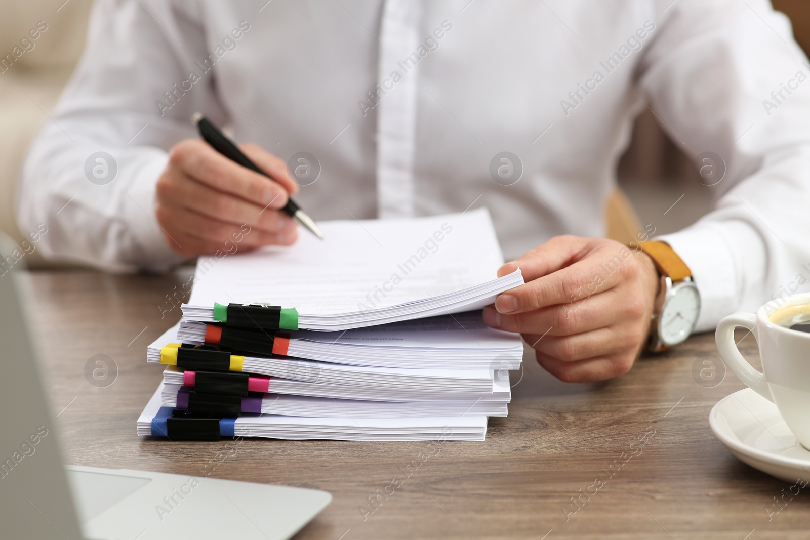 Photo of Man working with documents at wooden table in office, closeup