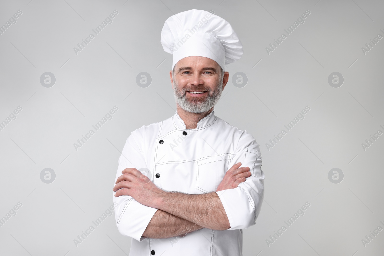 Photo of Happy chef in uniform on grey background