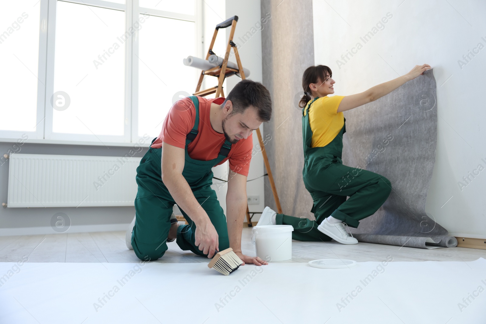 Photo of Workers hanging stylish gray wallpaper in room