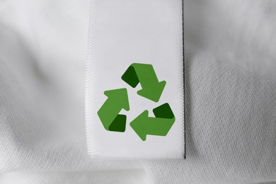 Image of Clothing label with recycling symbol on white shirt, closeup view
