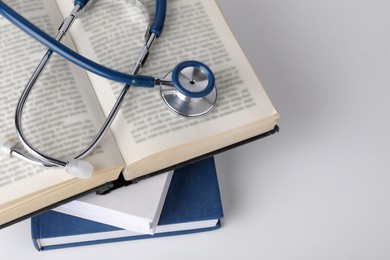 Photo of Student textbooks and stethoscope on white background, closeup. Medical education
