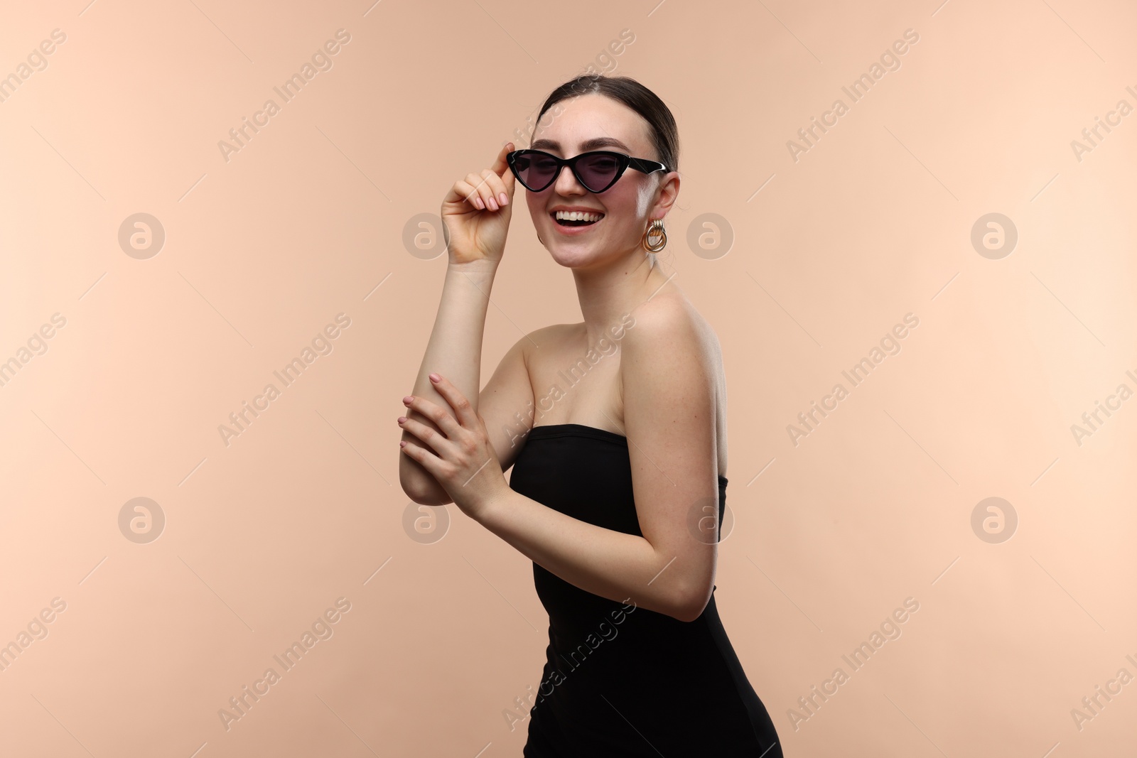 Photo of Portrait of beautiful young woman with sunglasses on beige background