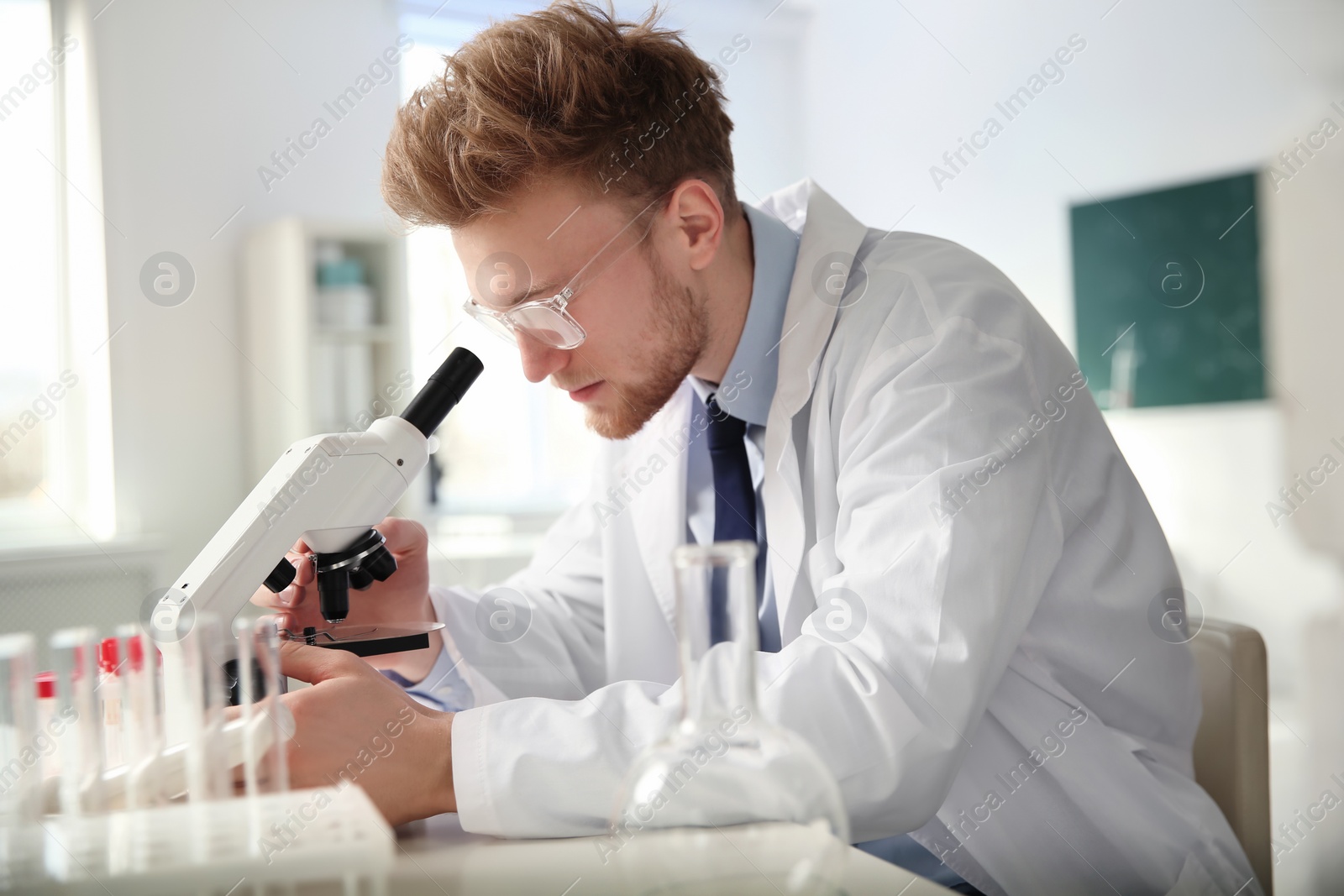 Photo of Male scientist using modern microscope in chemistry laboratory