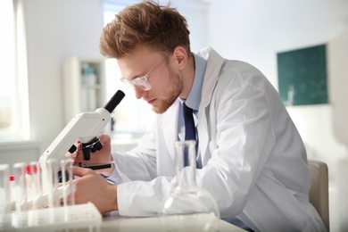 Male scientist using modern microscope in chemistry laboratory