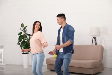 Happy couple dancing in living room at home