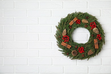 Photo of Beautiful Christmas wreath on white brick wall. Space for text