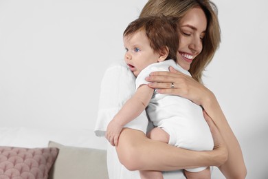 Photo of Mother hugging her cute little baby indoors, space for text