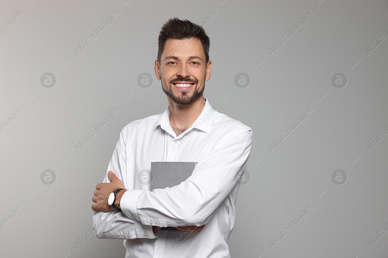 Photo of Happy teacher with book against beige background