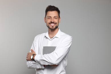 Happy teacher with book against beige background