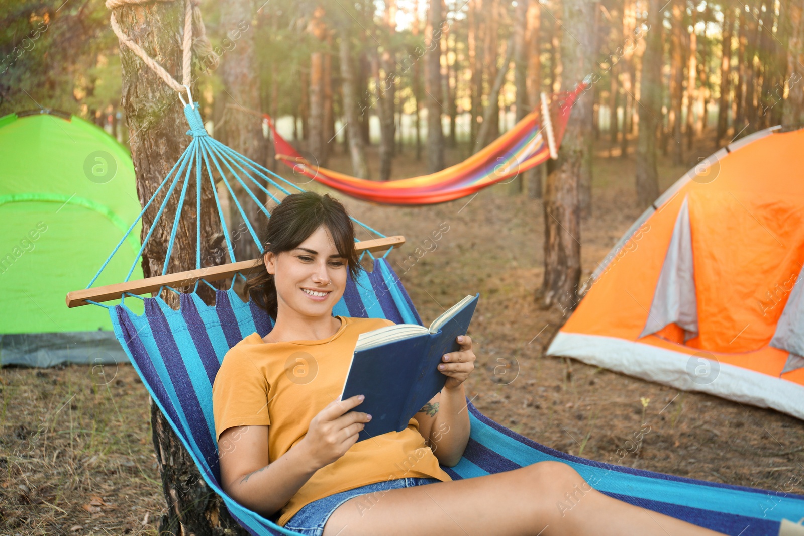 Photo of Woman with book resting in comfortable hammock outdoors