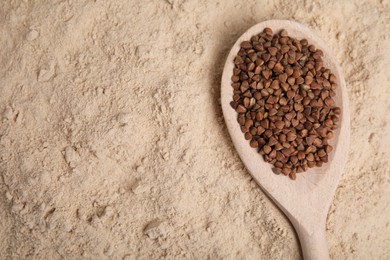 Photo of Spoon with buckwheat grains on flour, top view. Space for text