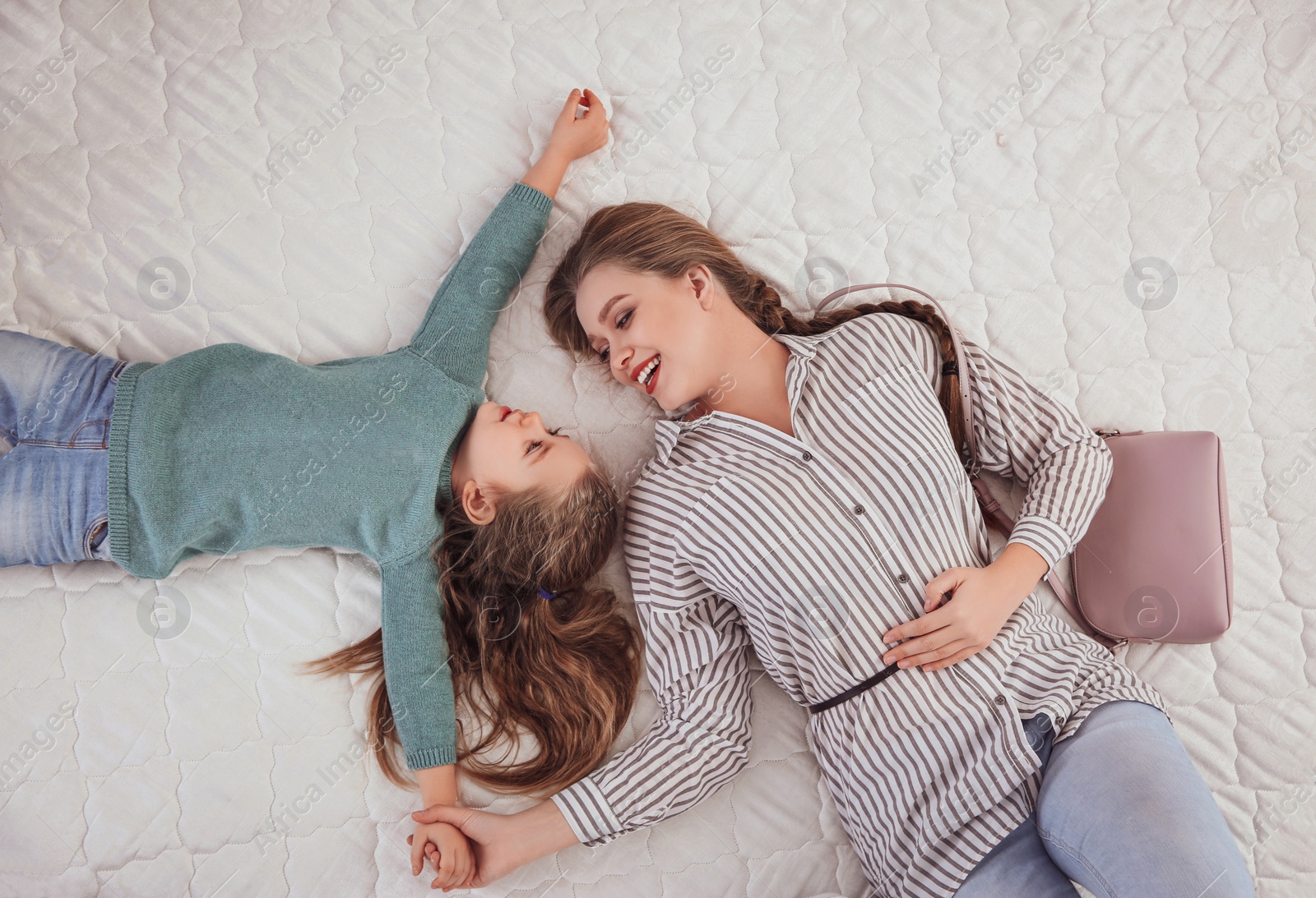 Photo of Mother and daughter testing mattress in store, top view