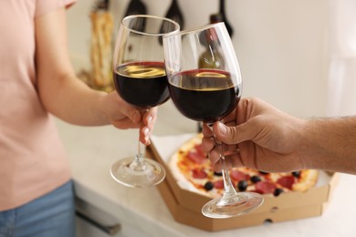 Couple clinking glasses of wine at home, closeup