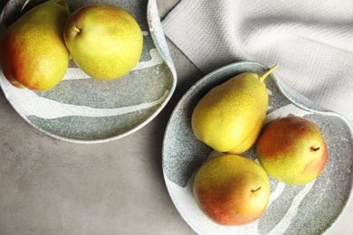 Photo of Plates with ripe juicy pears on grey stone table, flat lay