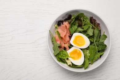 Photo of Delicious salad with boiled egg, salmon and arugula on white wooden table, top view
