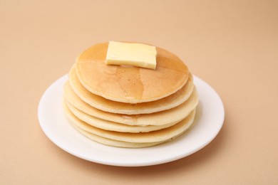 Photo of Delicious pancakes with butter and honey on beige background, closeup