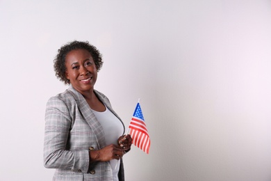 Portrait of happy African-American businesswoman with USA flag on white background