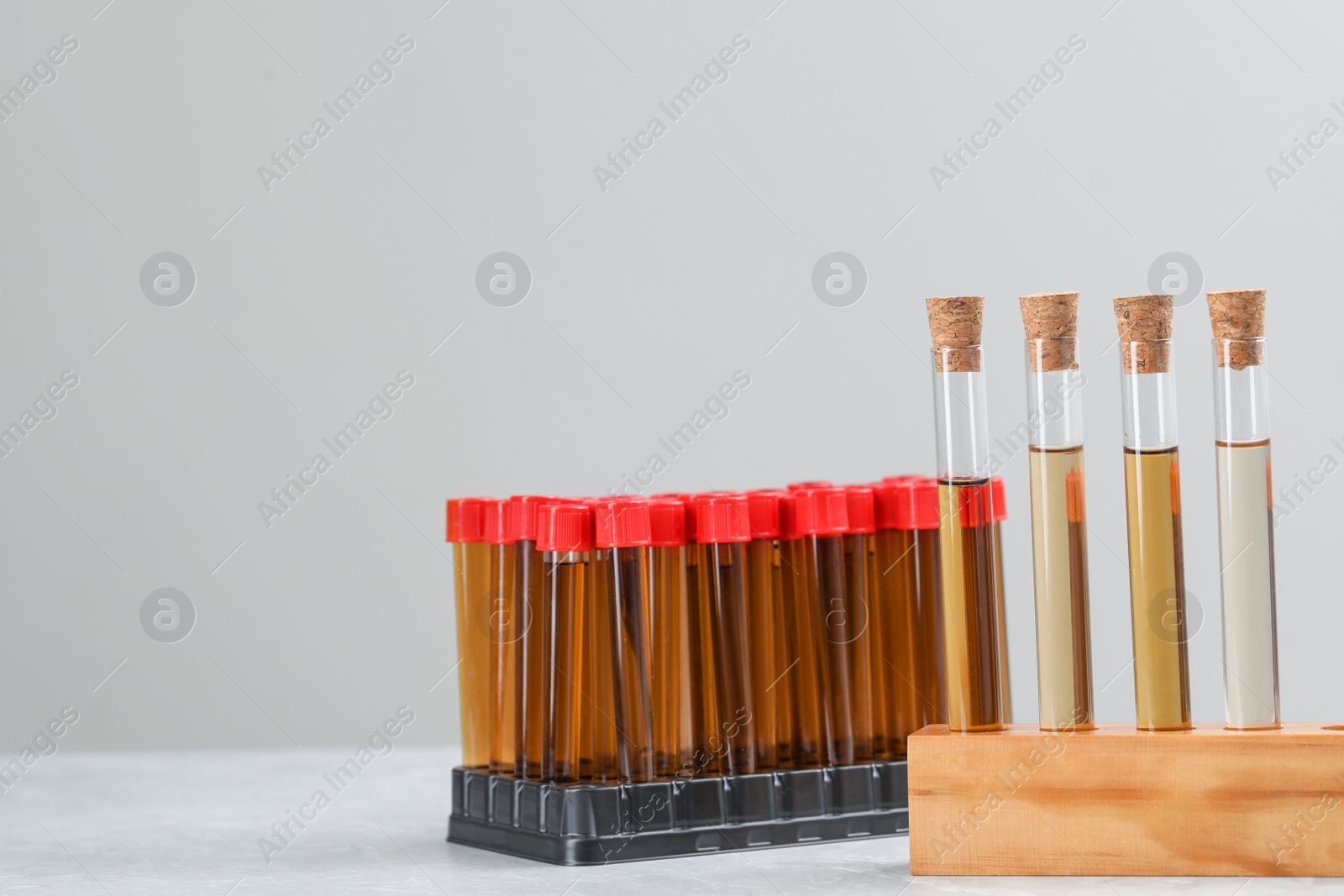 Photo of Test tubes with brown liquids in stands on white table against light background. Space for text