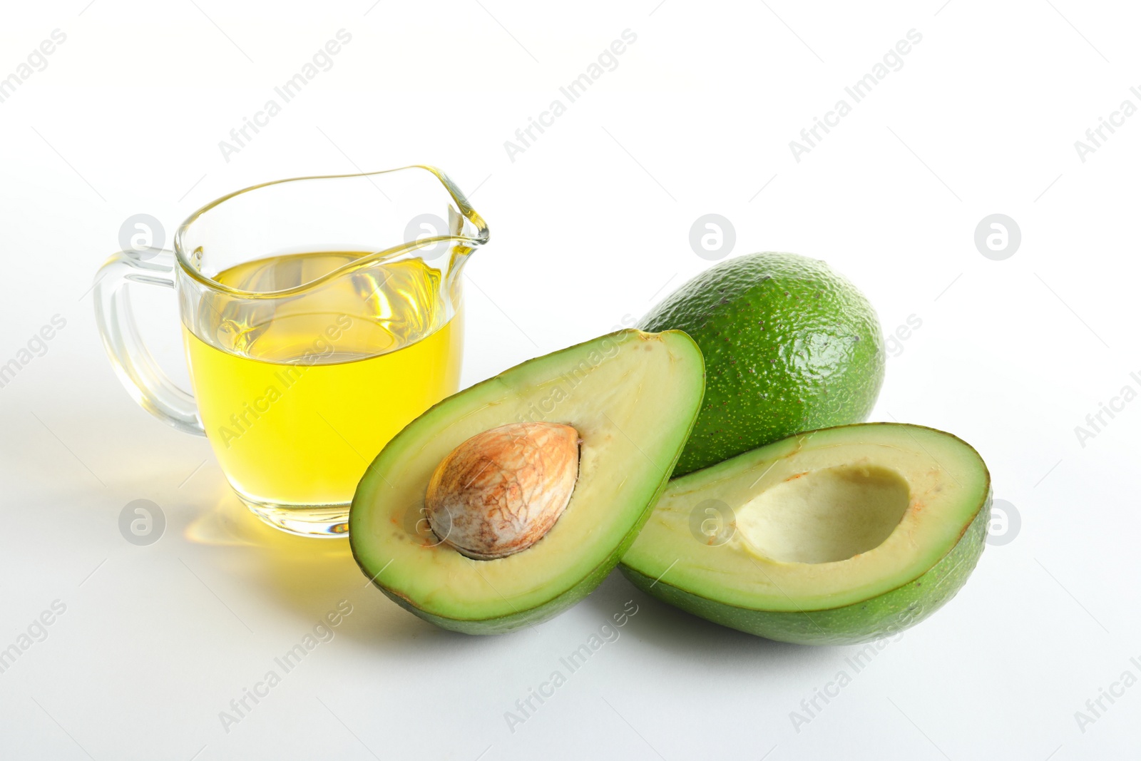 Photo of Gravy boat with oil and ripe fresh avocados on white background