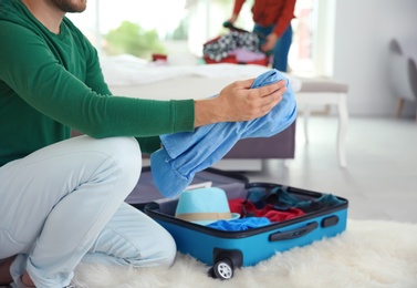 Young couple packing suitcases for summer journey at home