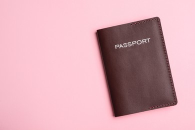Passport in brown leather case on pink background, top view. Space for text