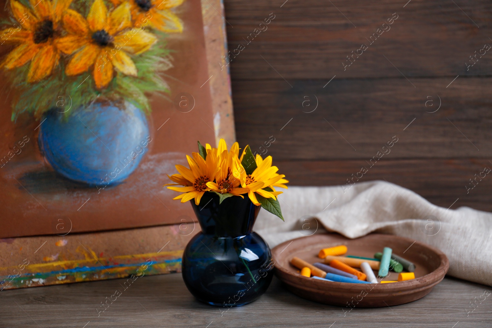 Photo of Yellow flowers, beautiful drawing and set of colorful pastels on wooden table