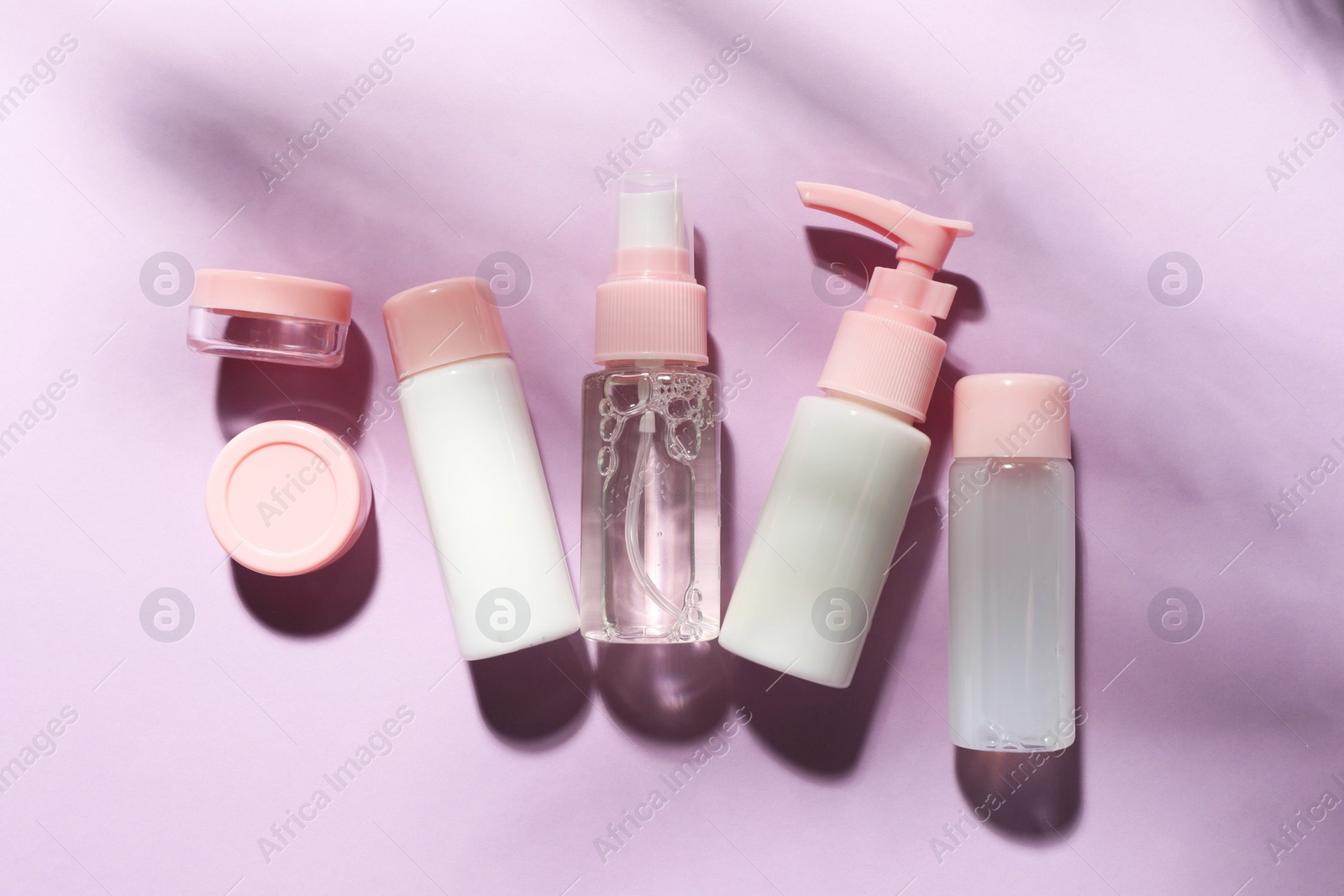 Photo of Cosmetic travel kit on violet background, top view