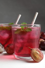 Photo of Delicious grape soda water and berries on white table. Refreshing drink