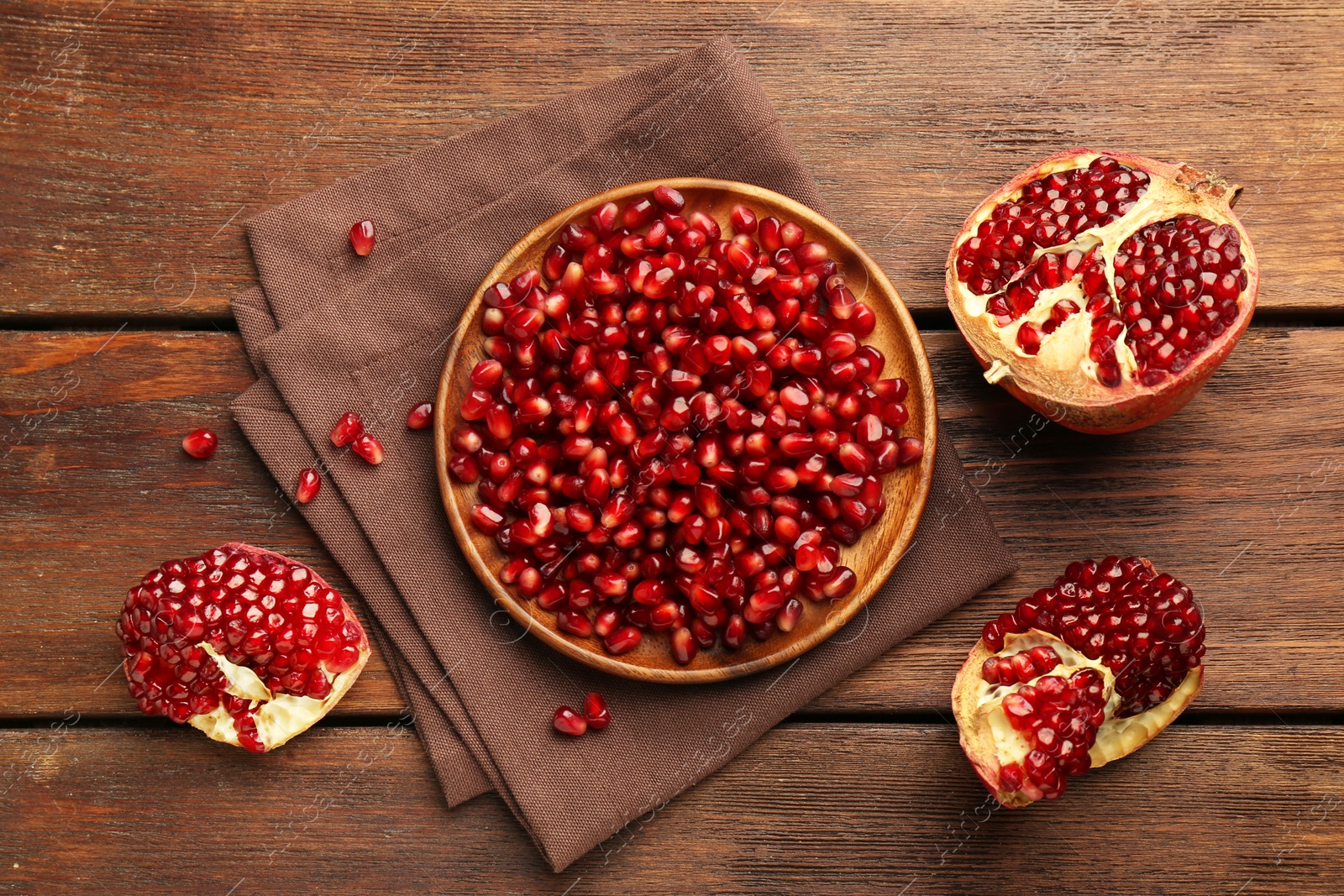 Photo of Ripe juicy pomegranates and grains on wooden table, flat lay