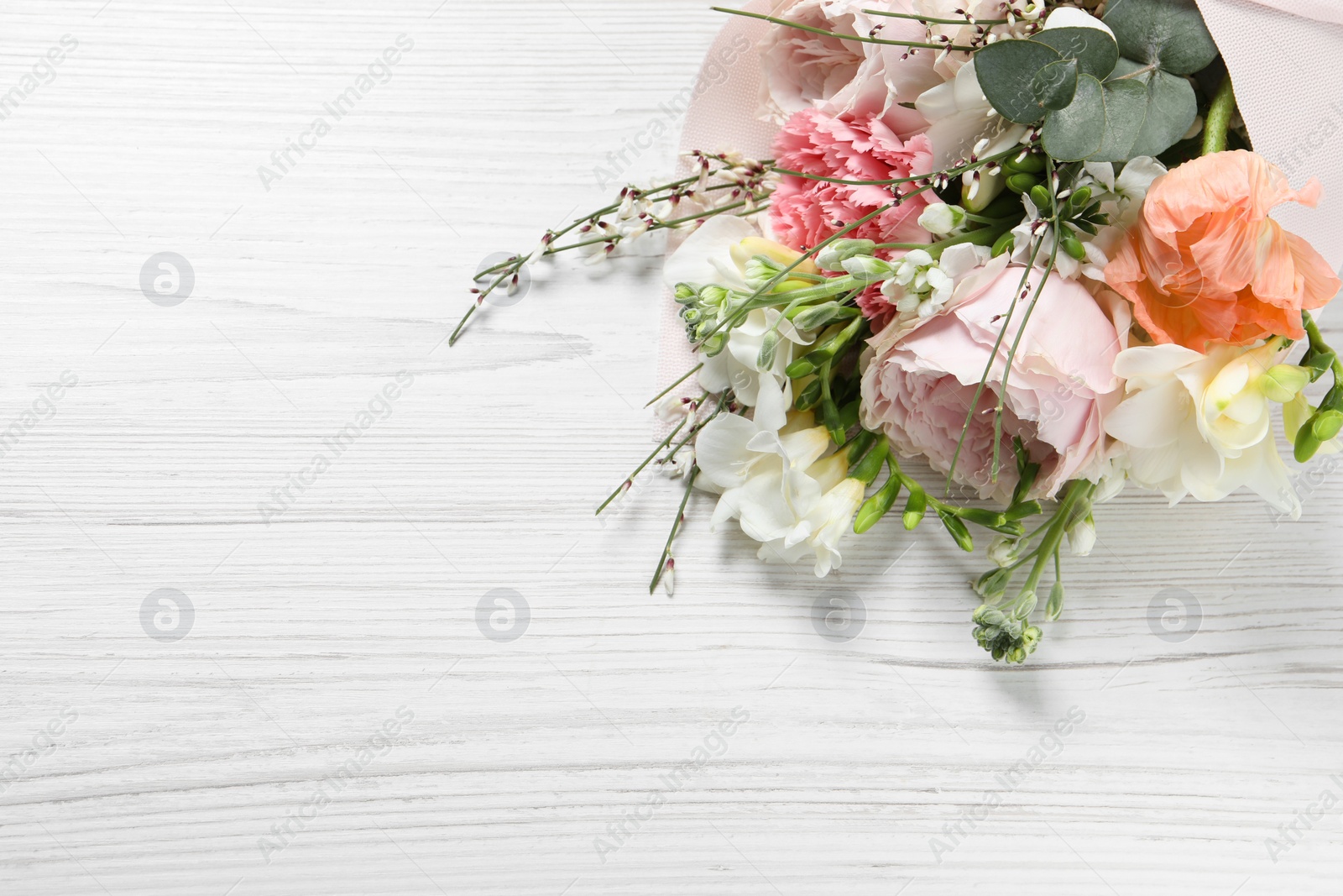 Photo of Bouquet of beautiful flowers on white wooden table, above view. Space for text