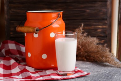 Photo of Can and glass of fresh milk on grey table