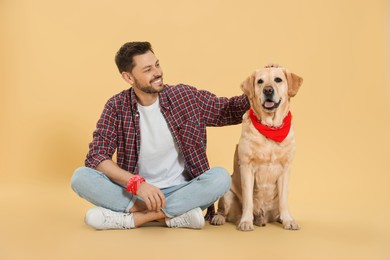 Photo of Happy man with his cute Labrador Retriever on beige background