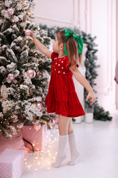 Photo of Cute little child near Christmas tree at home