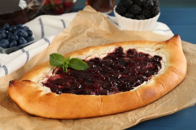 Delicious sweet cottage cheese pastry with cherry jam on blue table, closeup