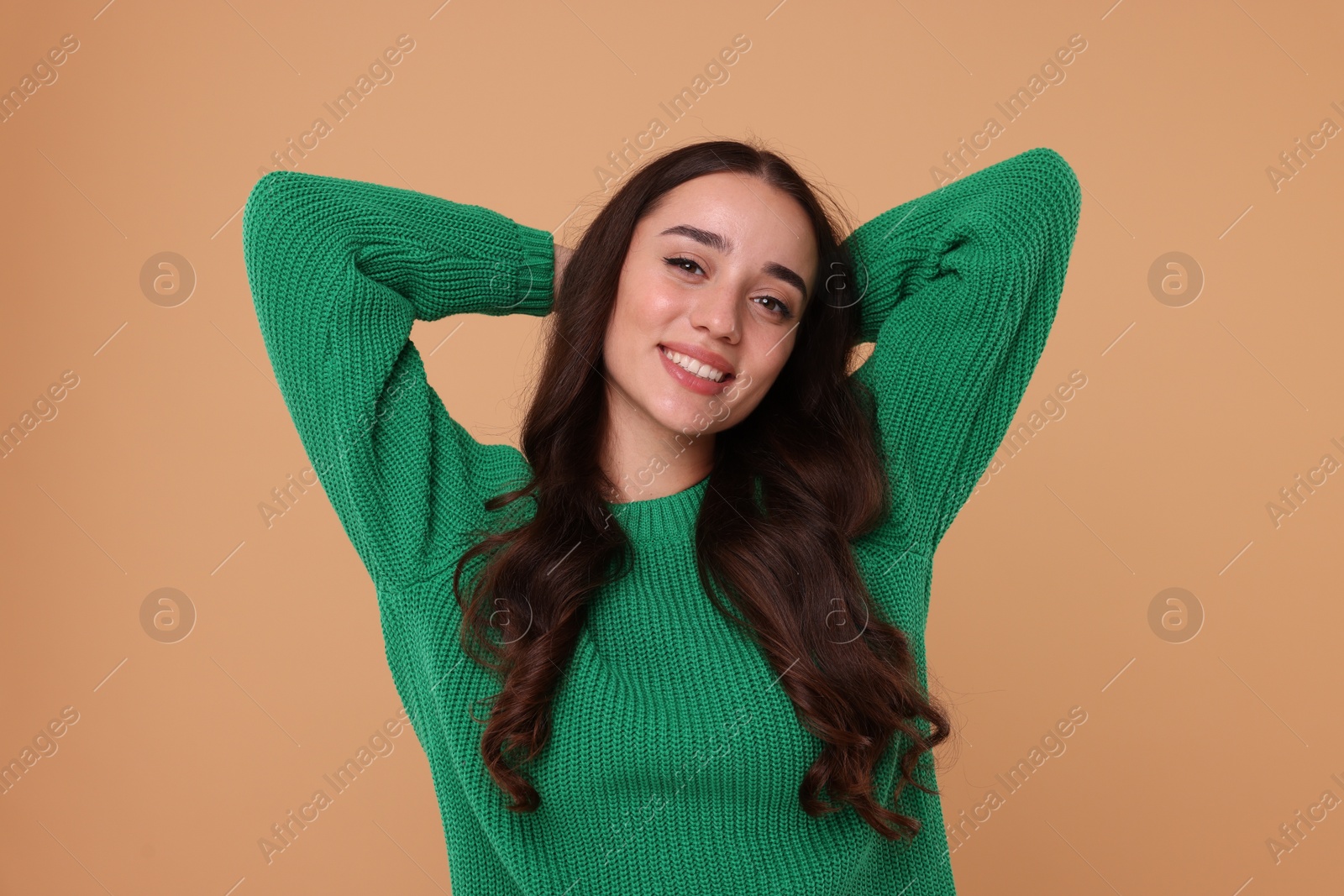 Photo of Beautiful young woman in stylish warm sweater on beige background