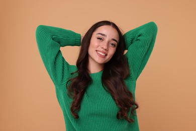 Photo of Beautiful young woman in stylish warm sweater on beige background