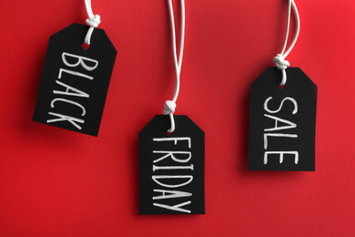 Tags with words BLACK FRIDAY SALE hanging on red background