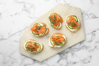 Photo of Tasty canapes with salmon, cucumber and cream cheese on white marble table, top view