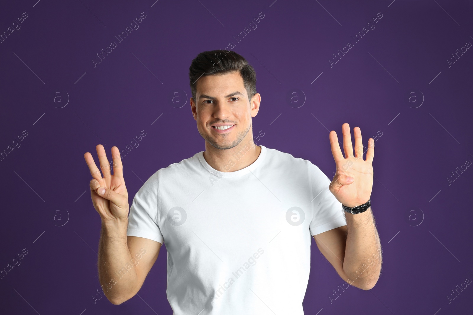 Photo of Man showing number seven with his hands on purple background