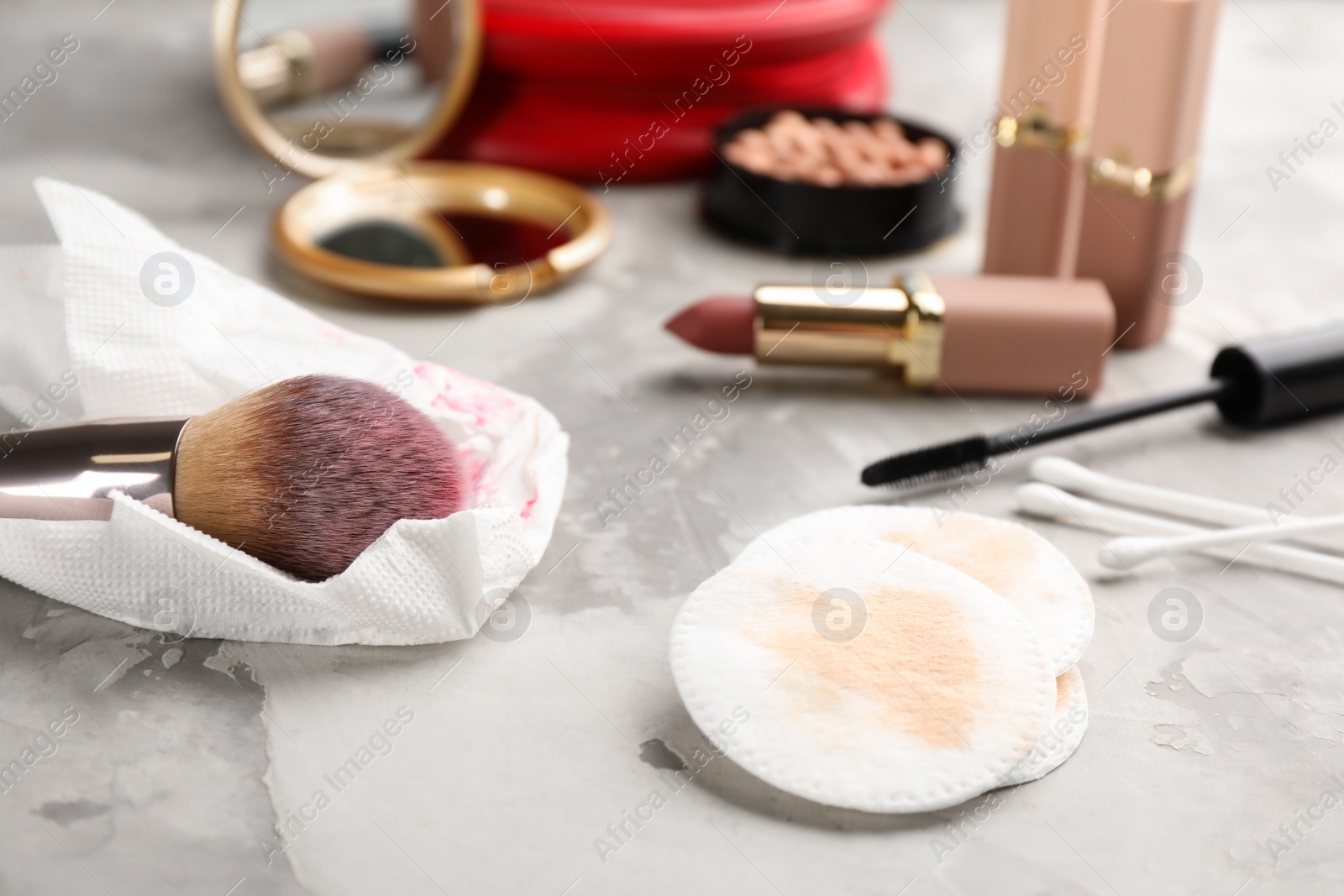 Photo of Dirty cotton pads, swabs, tissue and cosmetic products on grey table