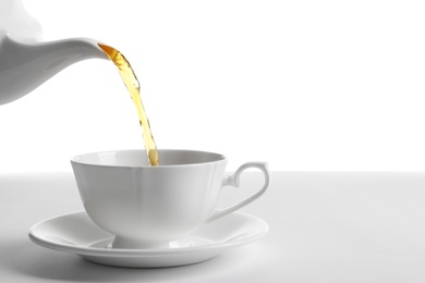 Photo of Pouring hot tea into porcelain cup on white background