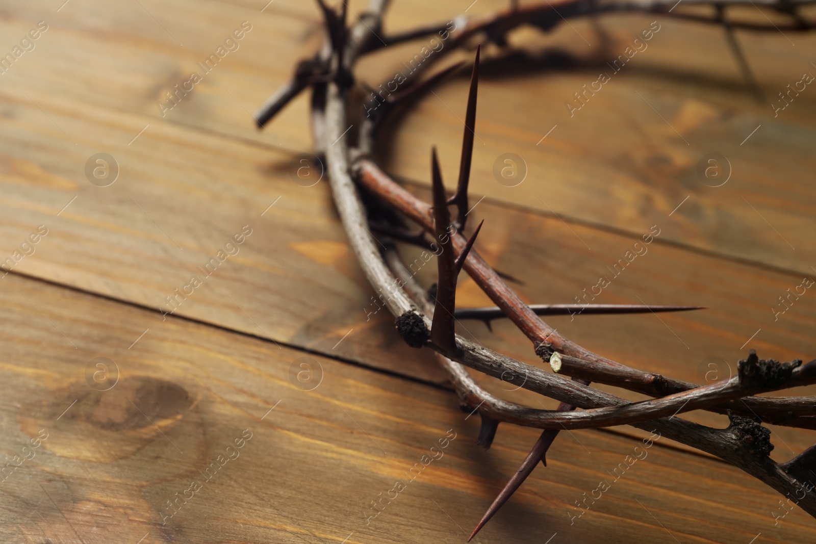 Photo of Crown of thorns on wooden table, closeup with space for text. Easter attribute