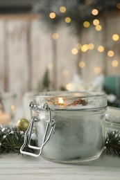 Burning scented conifer candle on white wooden table