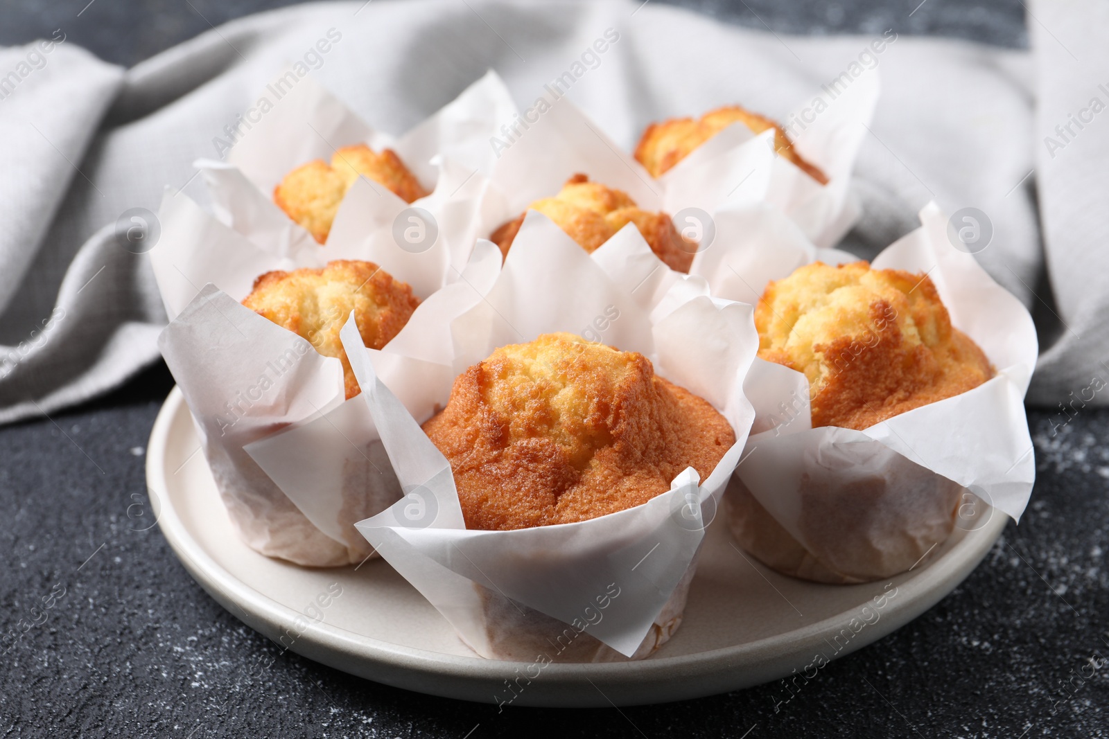 Photo of Delicious sweet muffins on black textured table, closeup