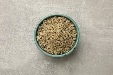 Fennel seeds in bowl on grey table, top view