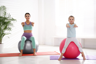 Woman and daughter doing exercise with fitness balls at home