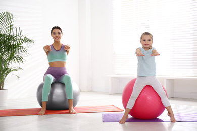 Photo of Woman and daughter doing exercise with fitness balls at home